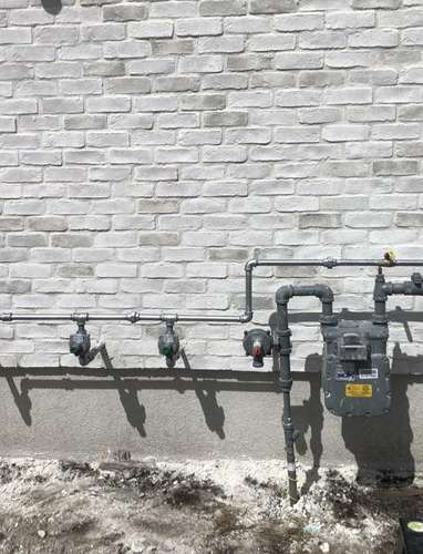 Gas meter manifold with branch lines on a brick home