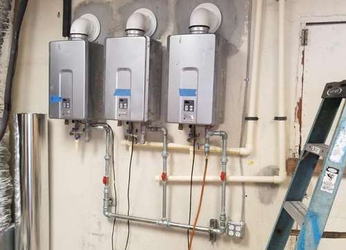 Three tankless gas water heaters installed on a wall